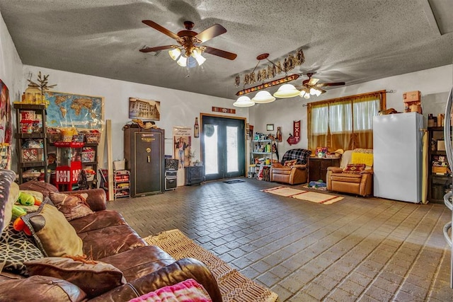 living room with ceiling fan, a textured ceiling, and french doors