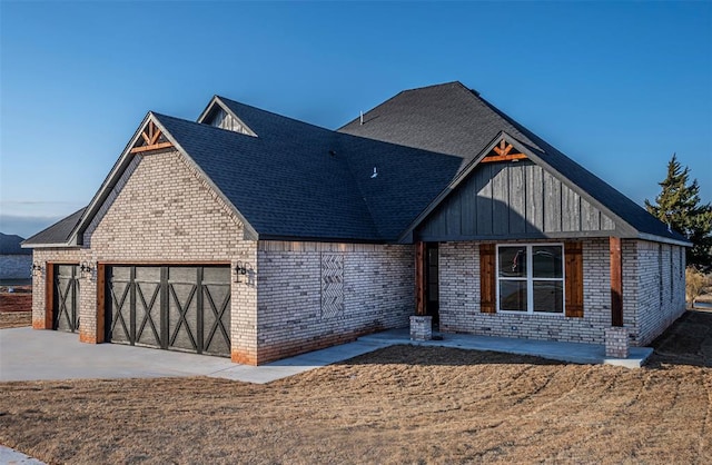 1127 Deer Rdg, Tuttle, OK 73089 - view of front of home with a garage, brick siding, board and batten siding, driveway, and a shingled roof