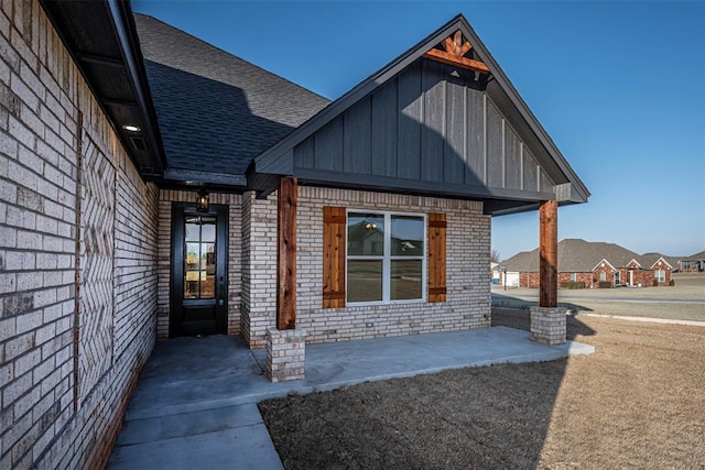 1127 Deer Rdg, Tuttle, OK 73089 - view of exterior entry with board and batten siding, brick siding, and roof with shingles
