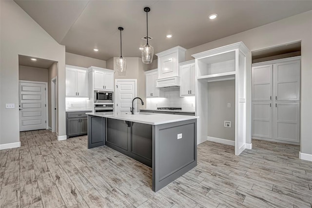 1127 Deer Rdg, Tuttle, OK 73089 - kitchen featuring stainless steel appliances, light countertops, backsplash, white cabinetry, and light wood finished floors