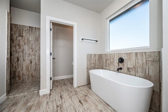 1127 Deer Rdg, Tuttle, OK 73089 - bathroom featuring a freestanding bath, tiled shower, tile walls, and wood finished floors