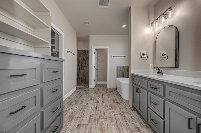 1127 Deer Rdg, Tuttle, OK 73089 - bathroom featuring double vanity, a freestanding tub, a tile shower, and wood finished floors