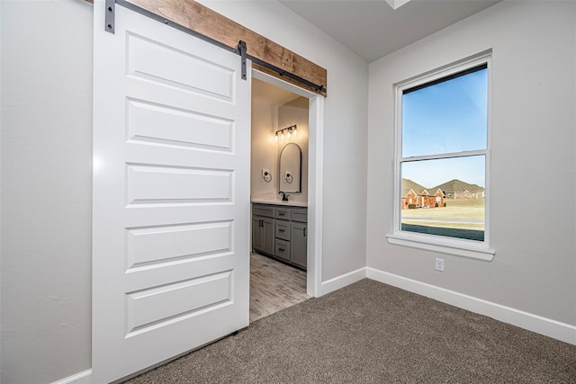 1127 Deer Rdg, Tuttle, OK 73089 - unfurnished bedroom with a barn door, light carpet, and connected bathroom