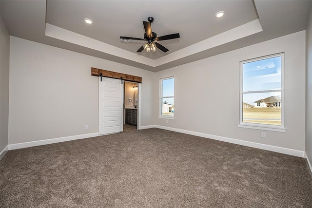 1127 Deer Rdg, Tuttle, OK 73089 - unfurnished bedroom featuring a raised ceiling, a barn door, dark colored carpet, recessed lighting, and ensuite bathroom