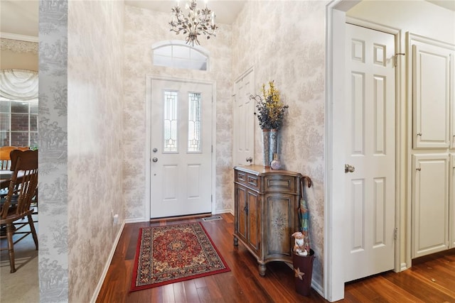 entryway featuring a notable chandelier, dark hardwood / wood-style flooring, and ornamental molding