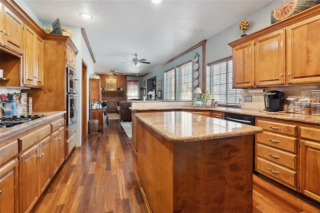 kitchen featuring dark wood-type flooring, decorative backsplash, a fireplace, a kitchen island, and stainless steel appliances