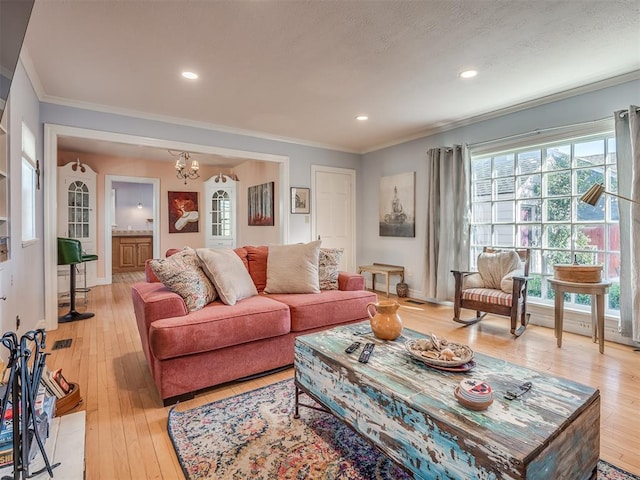 living room with a notable chandelier, crown molding, and light hardwood / wood-style floors