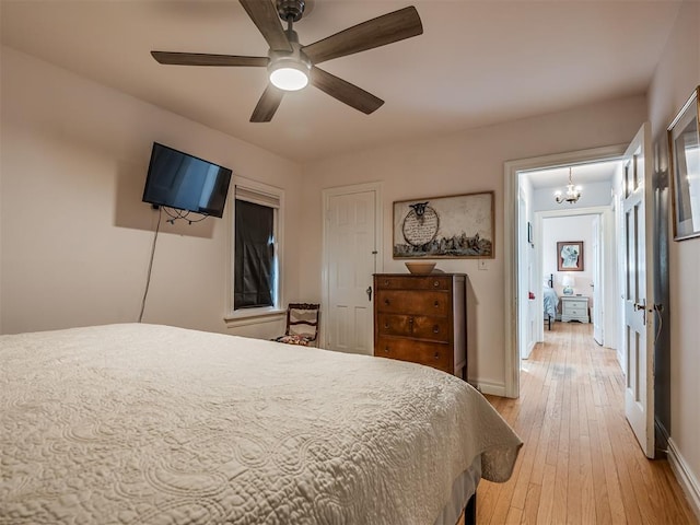 bedroom with ceiling fan with notable chandelier and light hardwood / wood-style floors