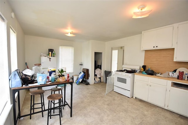 kitchen with white appliances, a kitchen bar, and white cabinetry