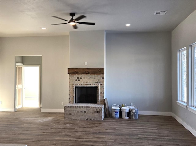 unfurnished living room featuring ceiling fan, dark hardwood / wood-style flooring, and a brick fireplace