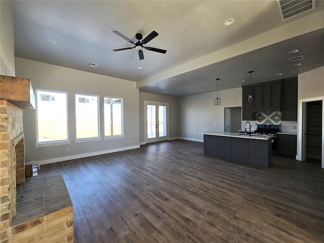 unfurnished living room with ceiling fan, sink, dark wood-type flooring, a stone fireplace, and french doors