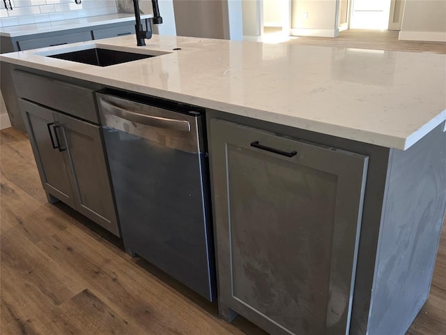 kitchen with dark wood-type flooring, sink, gray cabinetry, and a center island with sink