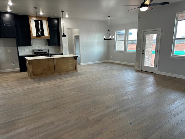 kitchen featuring open floor plan, light countertops, a sink, and wall chimney exhaust hood