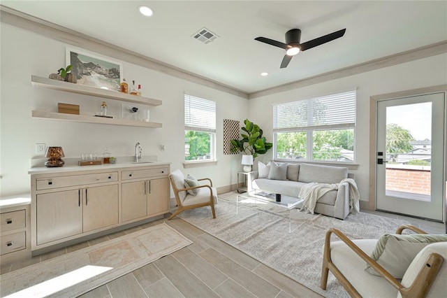 living room featuring sink, ceiling fan, and ornamental molding