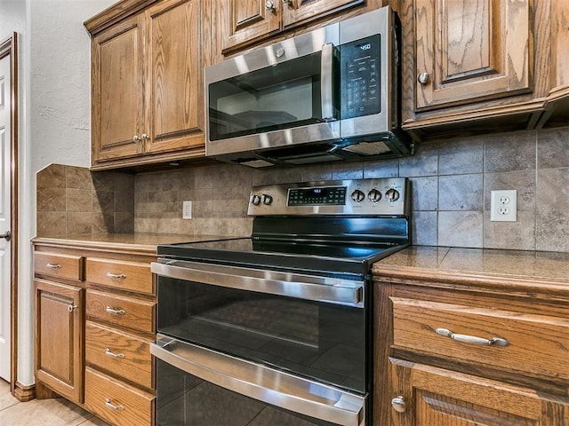 kitchen featuring appliances with stainless steel finishes, light tile patterned floors, and decorative backsplash