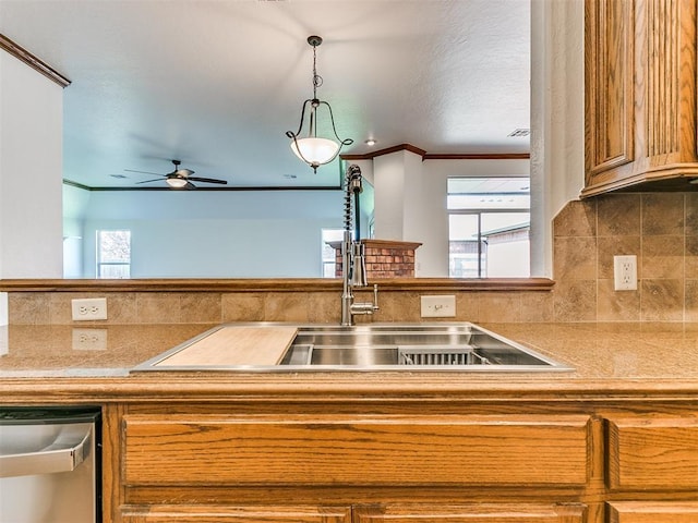 kitchen featuring pendant lighting, dishwasher, crown molding, and a healthy amount of sunlight