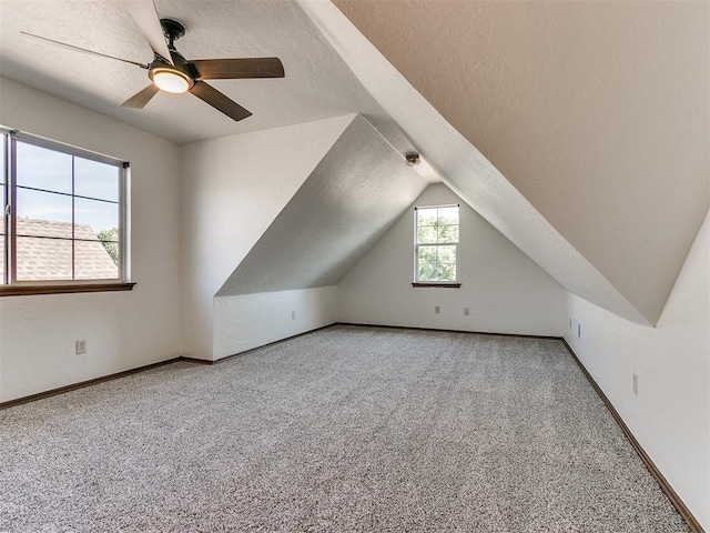 additional living space with vaulted ceiling, a textured ceiling, light carpet, and ceiling fan