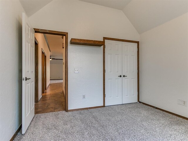 unfurnished bedroom with vaulted ceiling, light colored carpet, and a closet