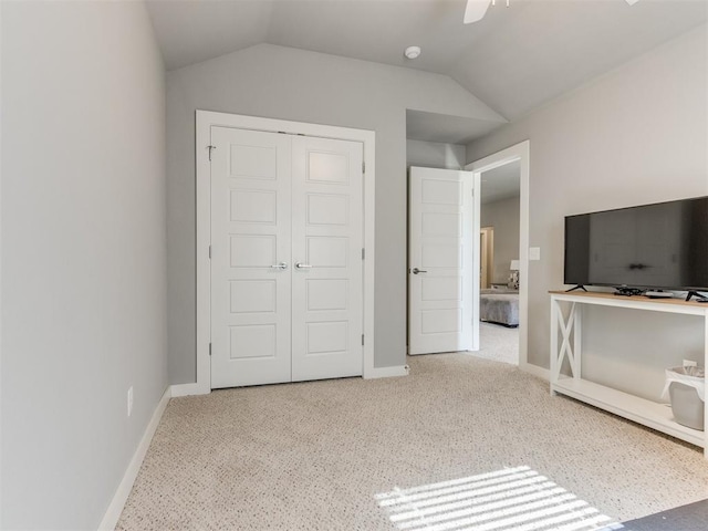 unfurnished bedroom featuring lofted ceiling, a closet, ceiling fan, and carpet