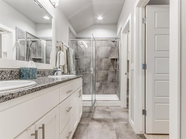 bathroom with a shower with door, vanity, and vaulted ceiling