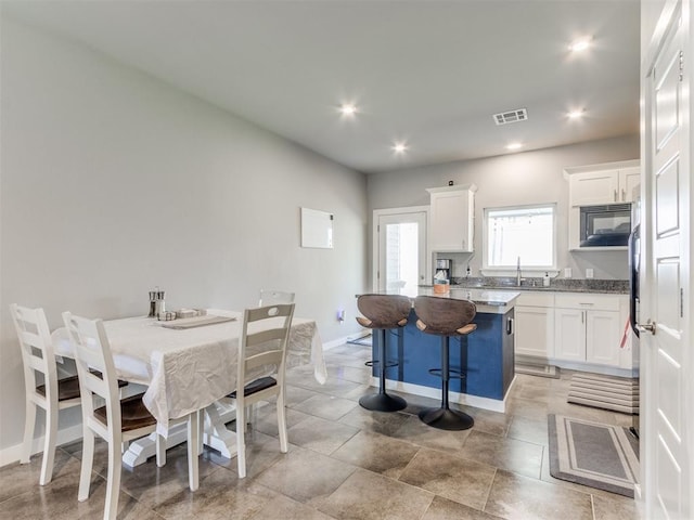 kitchen featuring sink, white cabinetry, a center island, and a kitchen bar