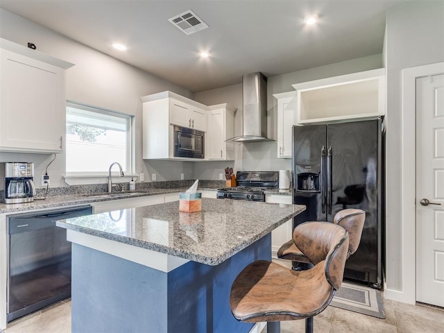 kitchen with black appliances, a center island, white cabinets, wall chimney range hood, and sink