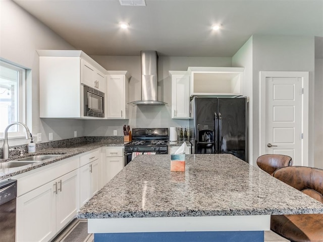 kitchen with black appliances, a center island, wall chimney range hood, and sink