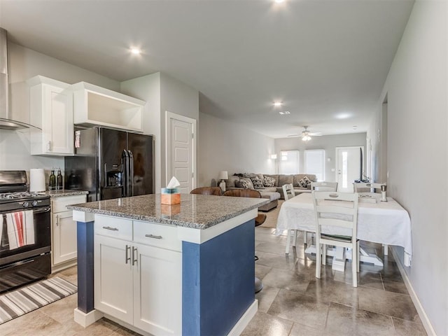 kitchen featuring black appliances, ceiling fan, a kitchen island, white cabinetry, and stone countertops