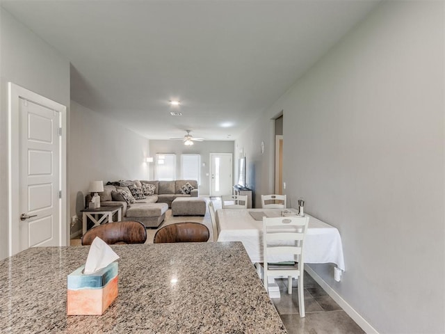 interior space with ceiling fan and light stone counters