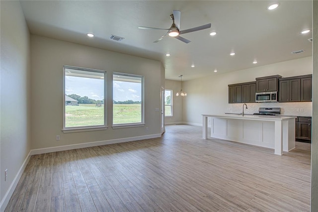 207 Hope Ave, Shawnee, OK 74804 - kitchen with stainless steel appliances, open floor plan, a ceiling fan, light wood-type flooring, and backsplash