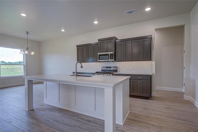 207 Hope Ave, Shawnee, OK 74804 - kitchen with appliances with stainless steel finishes, tasteful backsplash, light countertops, a chandelier, and light wood-type flooring