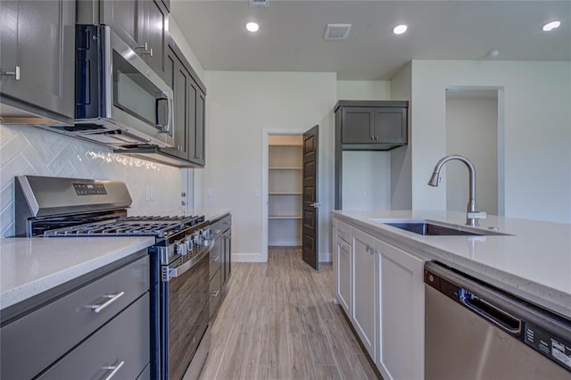207 Hope Ave, Shawnee, OK 74804 - kitchen with appliances with stainless steel finishes, backsplash, light wood-style floors, recessed lighting, and gray cabinets