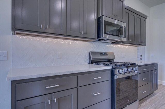 207 Hope Ave, Shawnee, OK 74804 - kitchen with stainless steel appliances, tasteful backsplash, light wood finished floors, and gray cabinetry