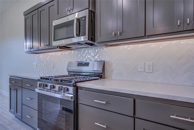 207 Hope Ave, Shawnee, OK 74804 - kitchen with appliances with stainless steel finishes, light stone counters, backsplash, and gray cabinets