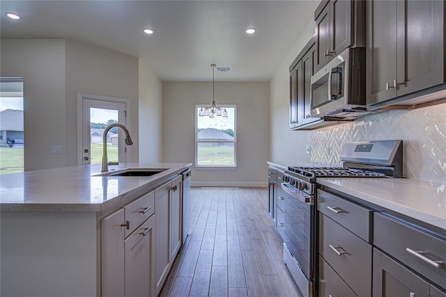 207 Hope Ave, Shawnee, OK 74804 - kitchen with stainless steel appliances, light wood finished floors, decorative backsplash, a chandelier, and healthy amount of natural light