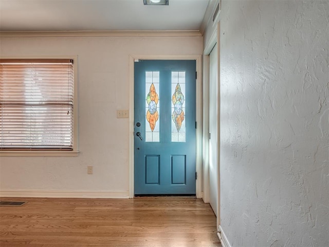 doorway with crown molding and light hardwood / wood-style flooring