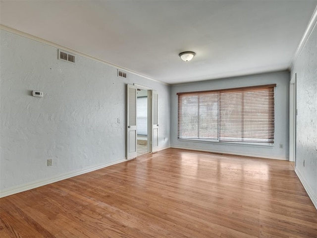 spare room with ornamental molding and light wood-type flooring