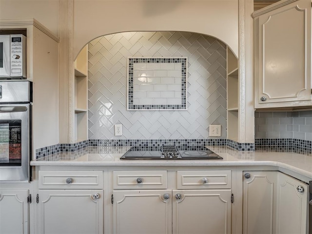 kitchen featuring black electric cooktop, white cabinets, oven, and decorative backsplash