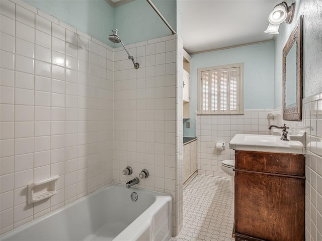 full bathroom with tiled shower / bath, tile walls, toilet, tile patterned floors, and vanity