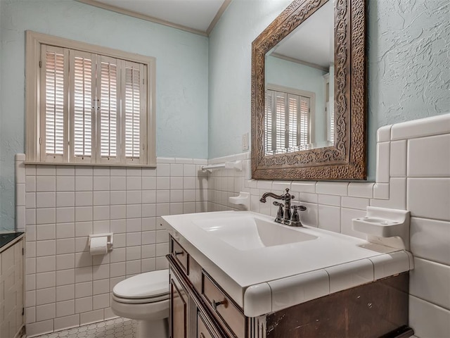 bathroom featuring toilet, tile patterned flooring, tile walls, crown molding, and vanity