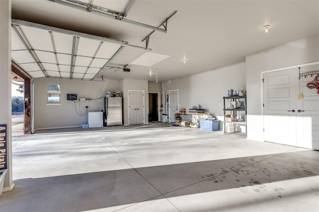 garage with a garage door opener and stainless steel refrigerator