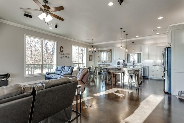 living room featuring ceiling fan with notable chandelier, ornamental molding, and sink