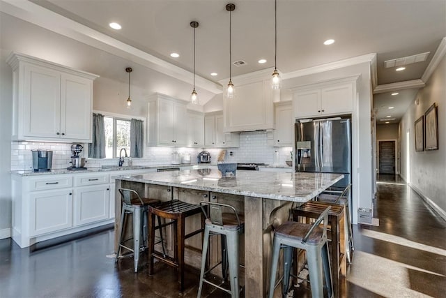 kitchen with white cabinets, decorative light fixtures, sink, and a spacious island