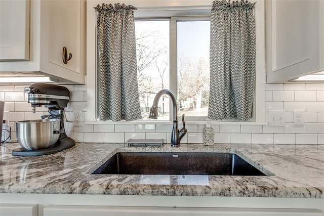 details featuring sink, light stone counters, and decorative backsplash