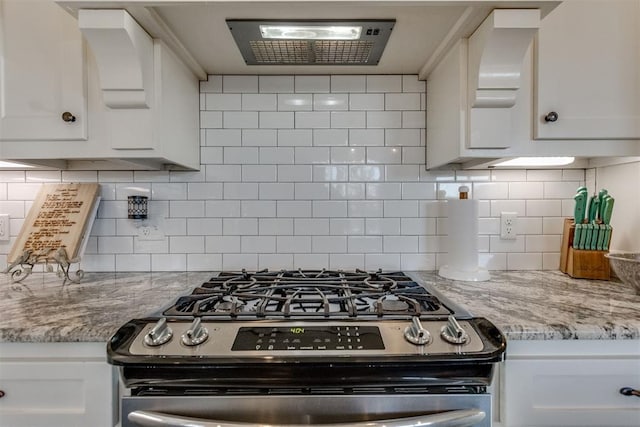 kitchen featuring light stone counters, stainless steel range with gas stovetop, tasteful backsplash, and white cabinetry