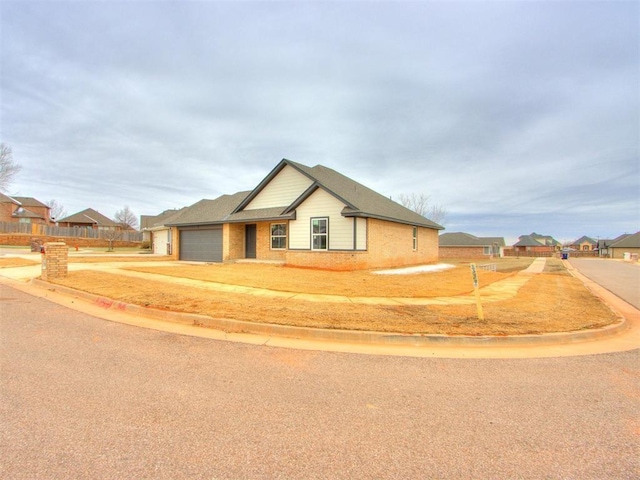 view of front of house with a garage, brick siding, fence, and a residential view