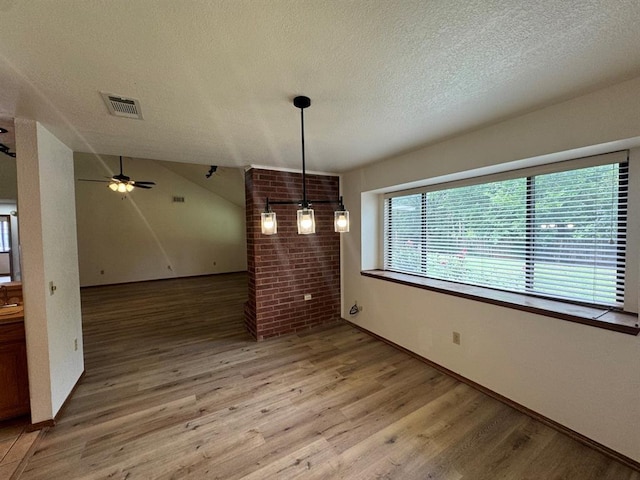 unfurnished dining area featuring ceiling fan, hardwood / wood-style floors, lofted ceiling, and a textured ceiling