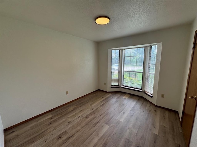 unfurnished room with light hardwood / wood-style floors and a textured ceiling