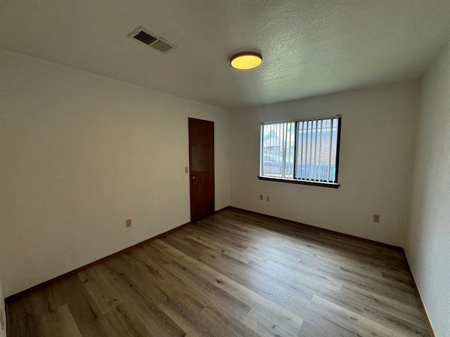 unfurnished room with a textured ceiling and light hardwood / wood-style flooring