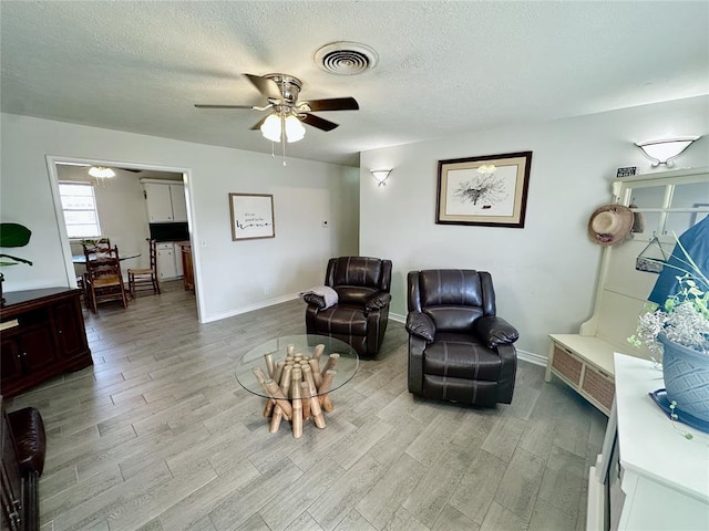 sitting room featuring a textured ceiling, ceiling fan, and light hardwood / wood-style flooring